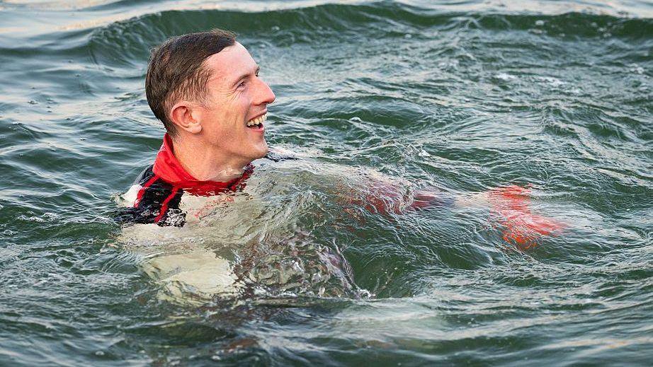 Elfyn Evans in water, smiling after his title win.