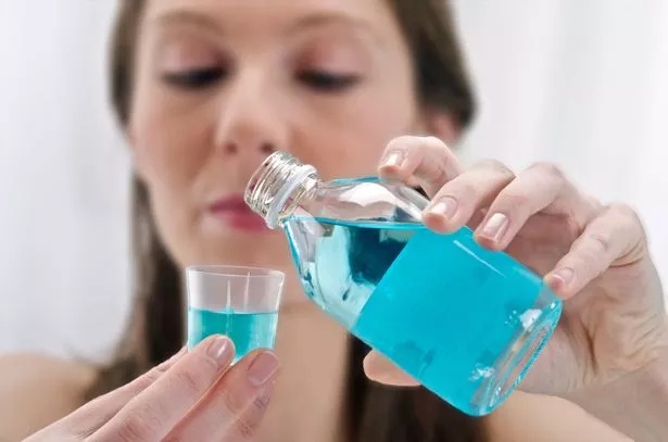 Woman seen pouring blue mouthwash into a cup