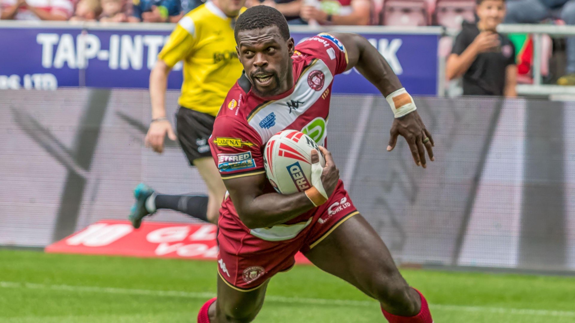 Christian Wade with the ball in his right hand about to dive down to score a try for Wigan Warriors