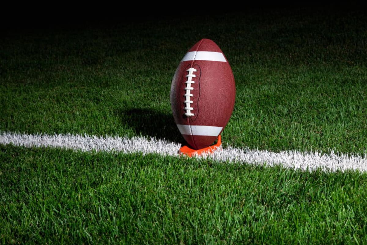 Football on a kicking tee on field's yard marker