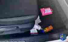 A baby bottle and juice is seen in the footwell of the car