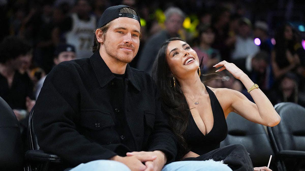 Justin Herbert and Madison Beer stand together at a basketball game.
