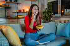 a photo of a woman having a snack on the couch