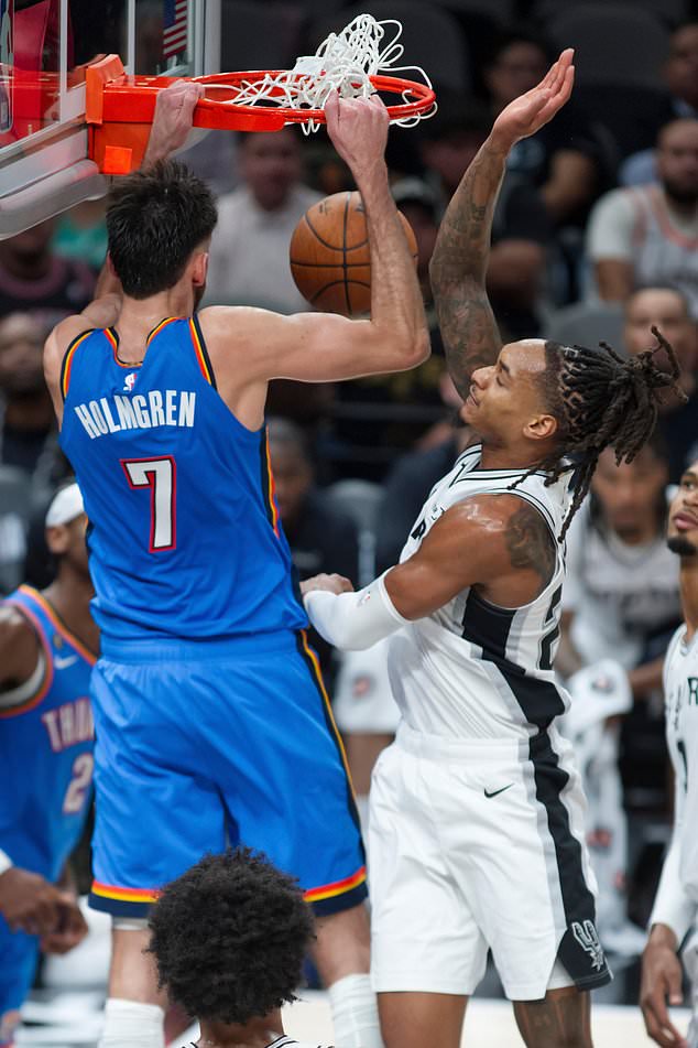 Oklahoma City Thunder center Chet Holmgren (7) dunks against San Antonio Spurs guard Devin Vassell during the first half of an NBA basketball game, Tuesday, Oct. 20, 2026, in San Antonio. (AP Photo/Darren Abate)