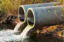 Two concrete pipes discharging dirty water into river.