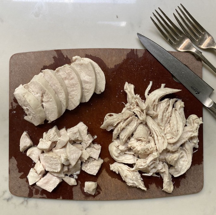 shredded sliced and chopped chicken on a cutting board