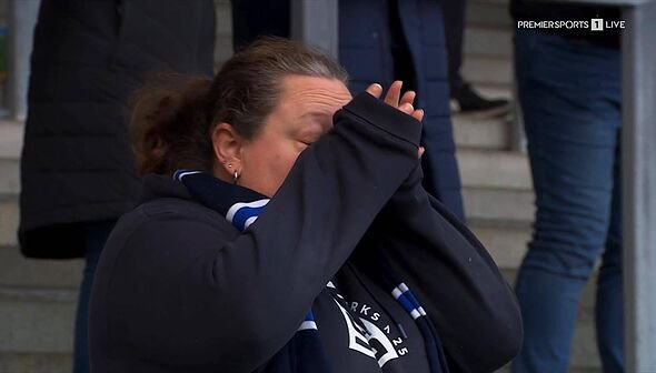 An individual, possibly a sports coach or team member, is visibly distraught, covering their face with their hands while standin