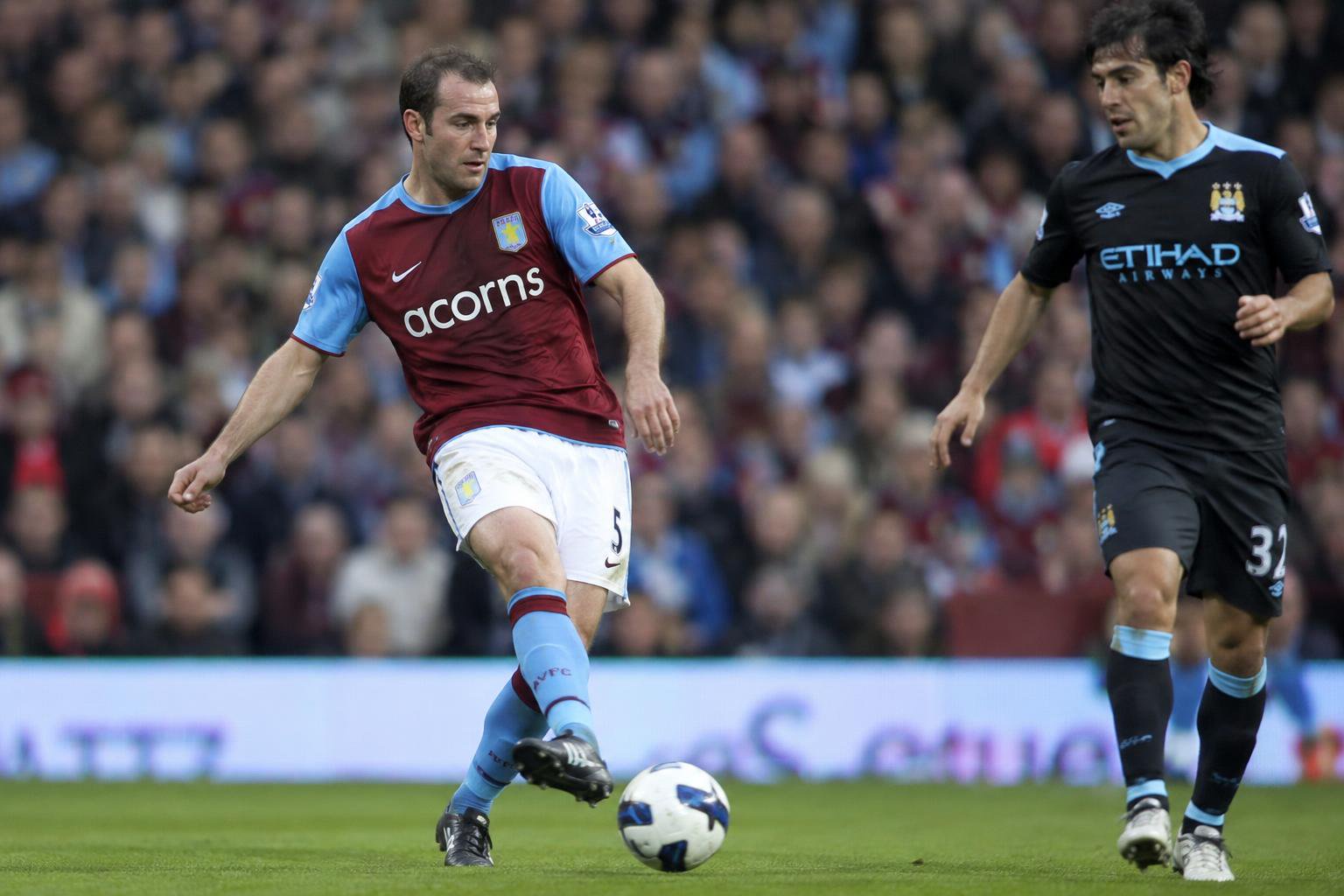 Aston Villa's Richard Dunne in his early 30s is passing the ball in Villa Park against Manchester City in the 2009/10 season