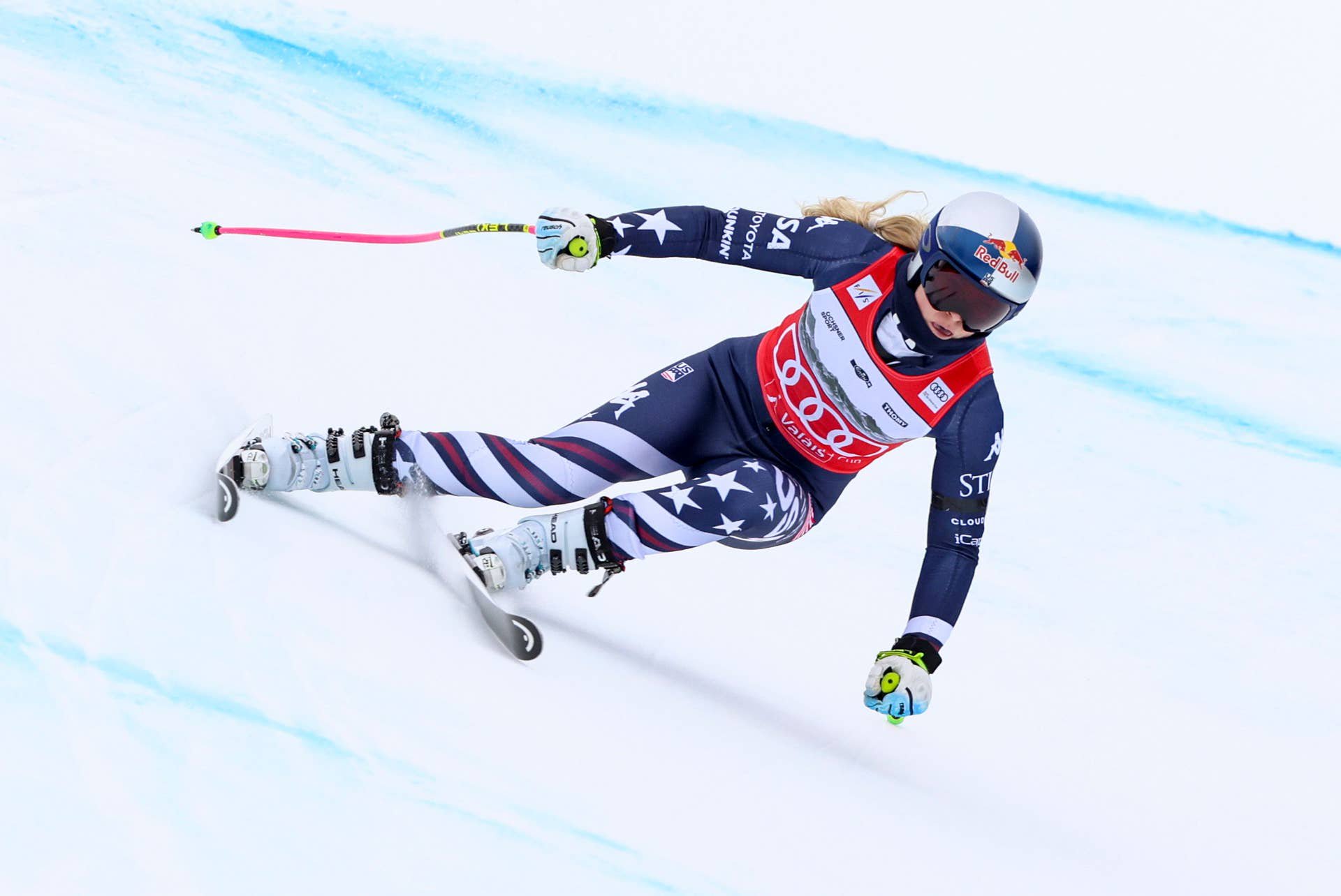 Eine Skirennläuferin fährt in voller Geschwindigkeit eine Abfahrt auf einer verschneiten Piste hinunter.