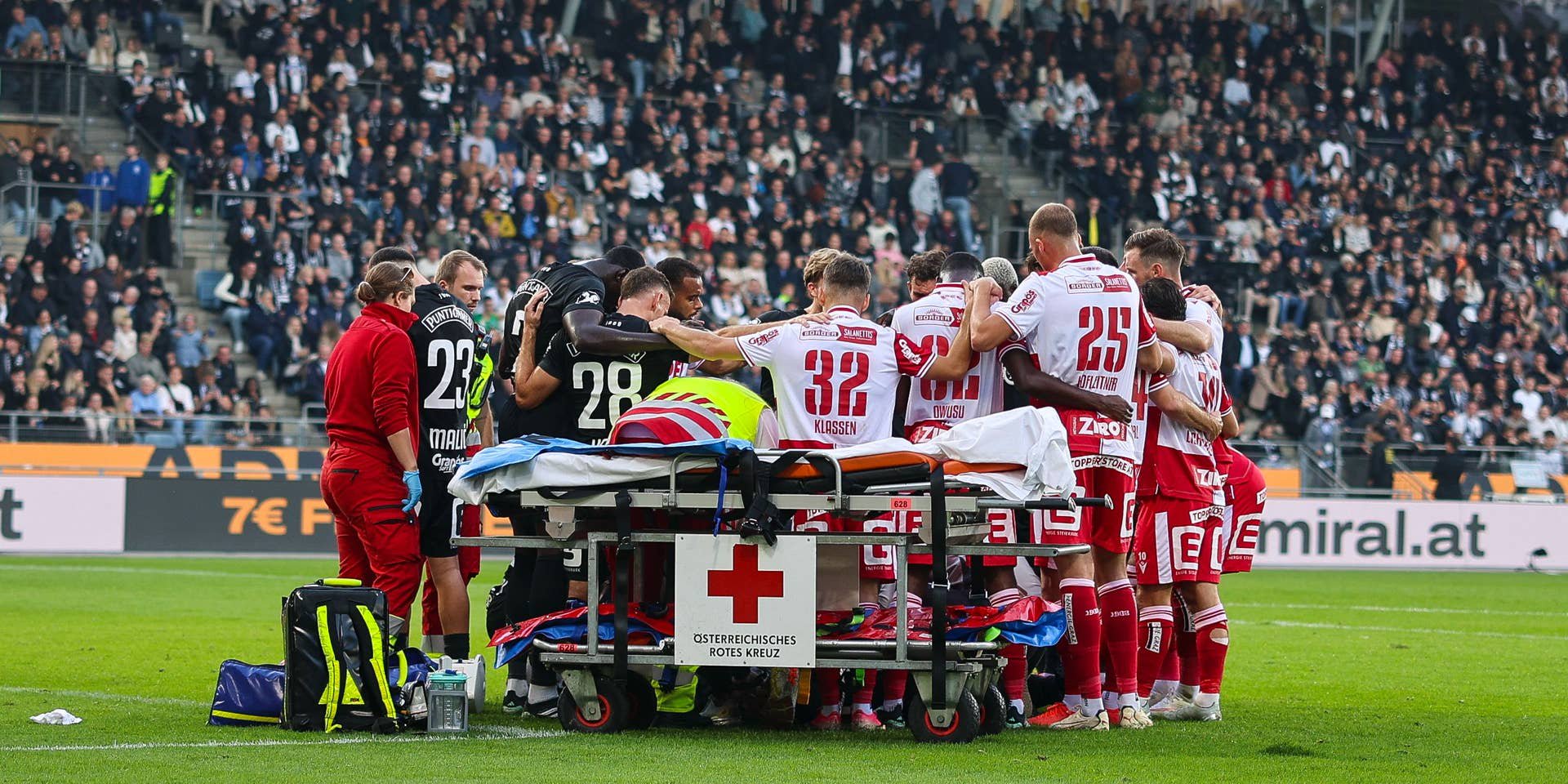 Spieler beider Teams bilden einen Sichtschutz um den schwer verletzten Sturm-Goalie Daniil Khudyakov, der unter dem Applaus der Fans abtransportiert wird.