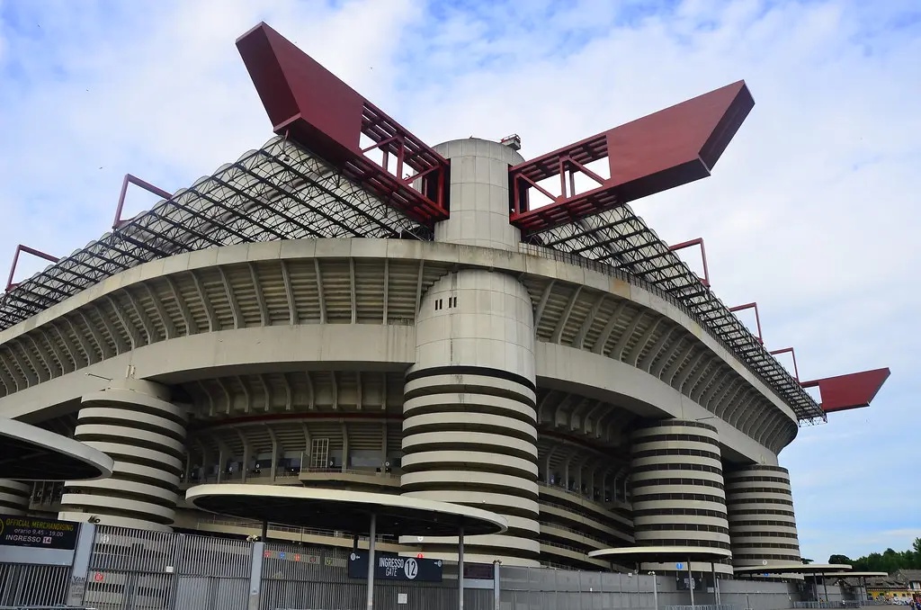 External view of the San Siro stadium in Milan showing its distinctive architecture and red roof structures.