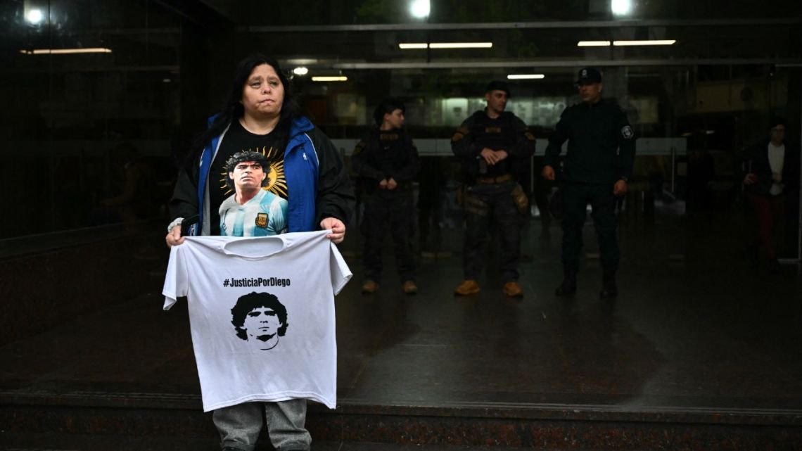 A supporter of Argentine football legend Diego Maradona holds a T-shirt  outside the San Isidro courthouse during the final hearing of defense closing arguments in the trial over Maradona's death, in San Isidro, Buenos Aires Province, Argentina, on October 21, 2026. 
