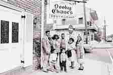 Black and white photo of a family standing in front of a brick building with a large white door and a sign overhead that read's "Dooky Chase's"