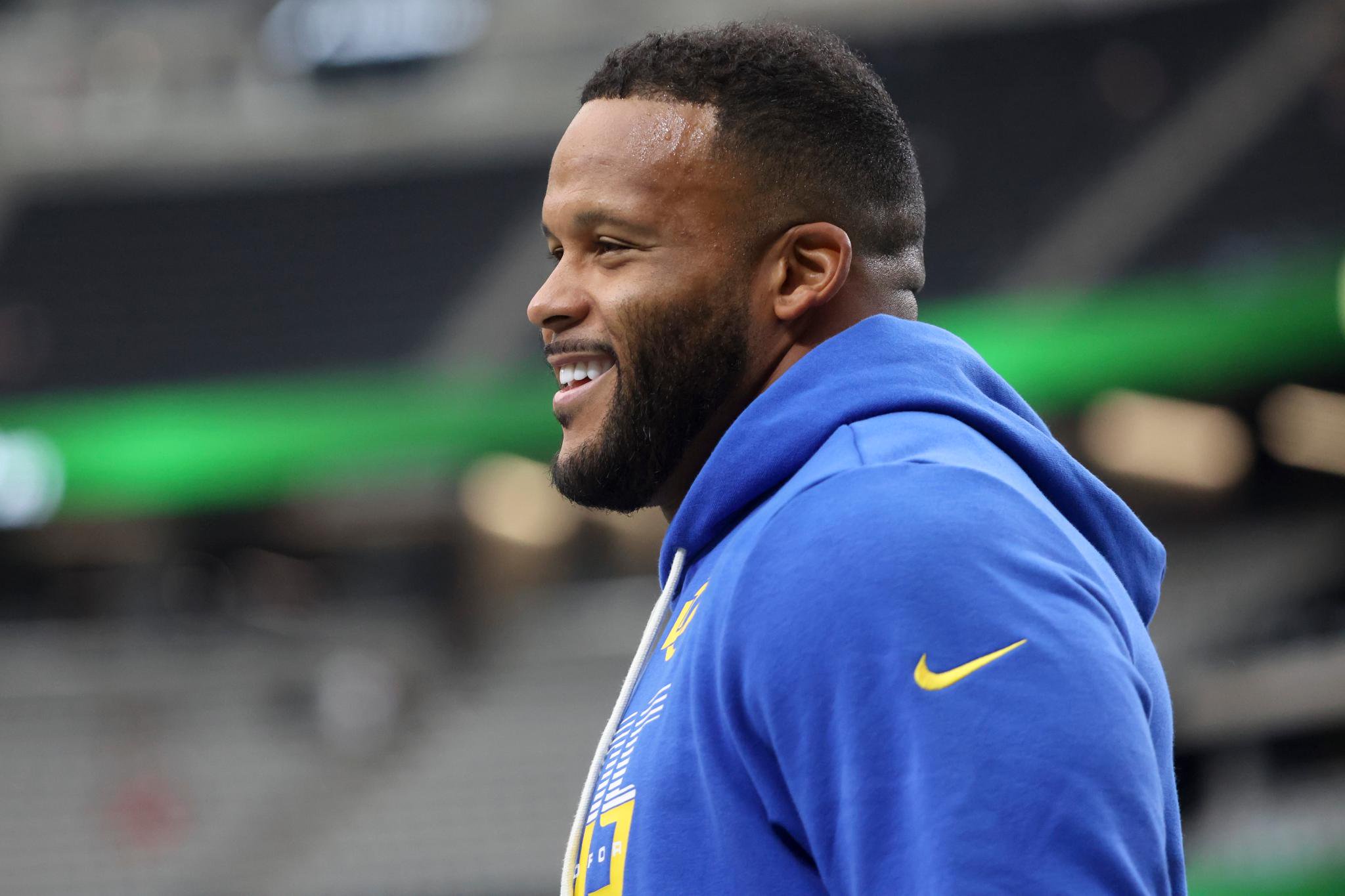 Los Angeles Rams player Aaron Donald smiling on the sideline during a game against the Las Vegas Raiders.