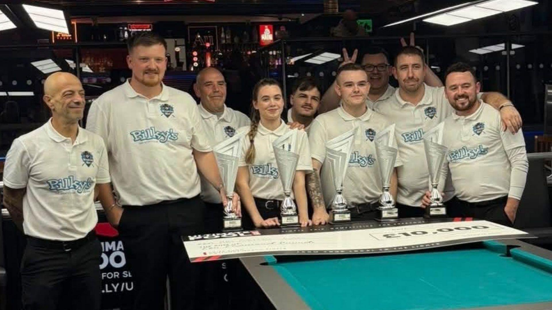 Eight men and one woman in white polo shirts stand behind a pool table