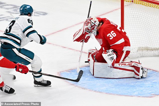 Detroit Red Wings goaltender John Gibson, right, stops a shot from San Jose Sharks center Zack Ostapchuk during the first period of an NHL hockey game, Saturday, Oct. 17, 2026, in Detroit. (AP Photo/Jose Juarez)