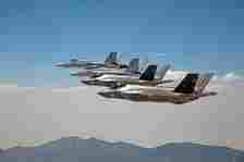 Several F-35Cs Lightning II and F/A-18F Super Hornets flying in the sky.