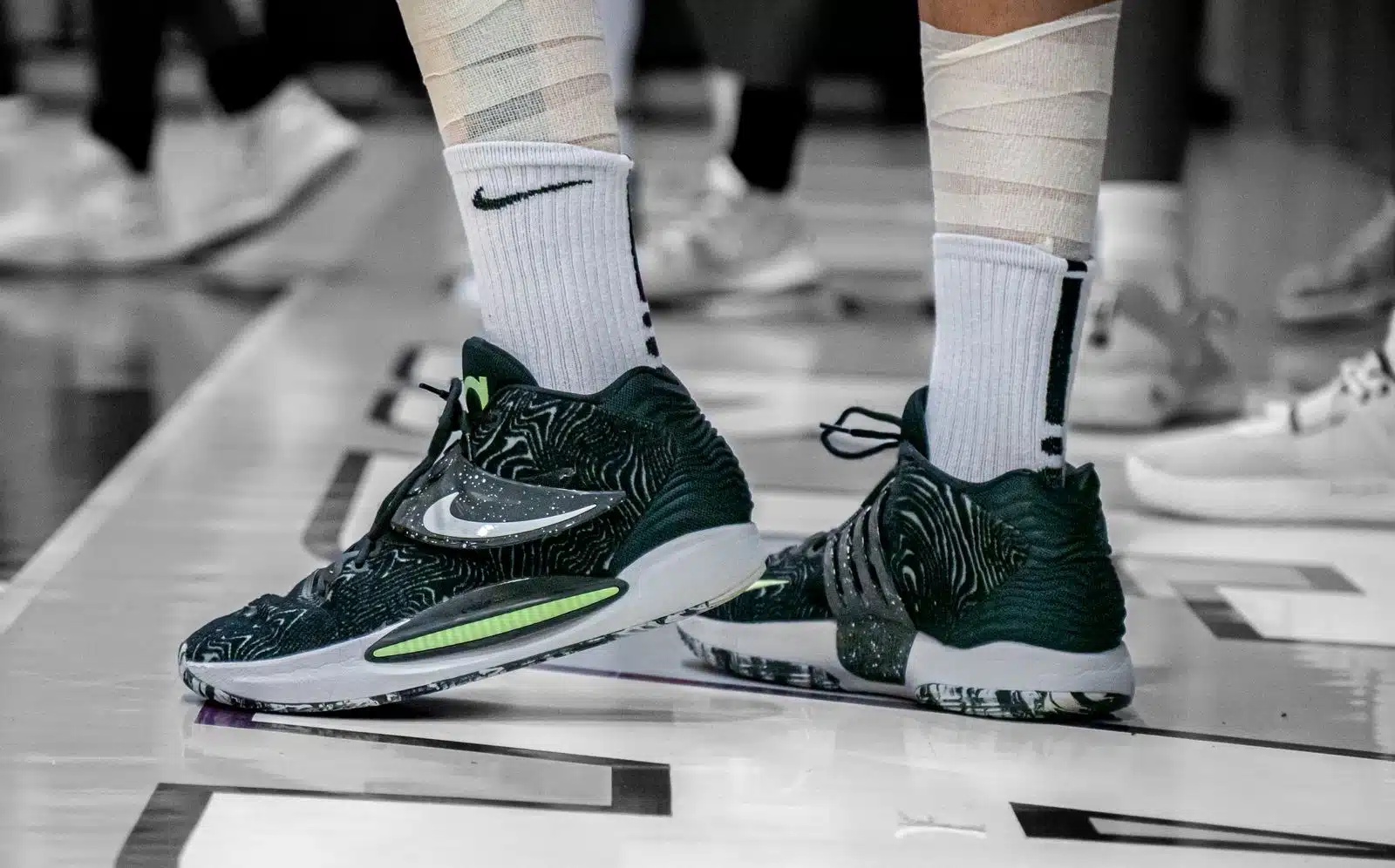 Basketball player in taped socks and high-top sneakers standing on an indoor court