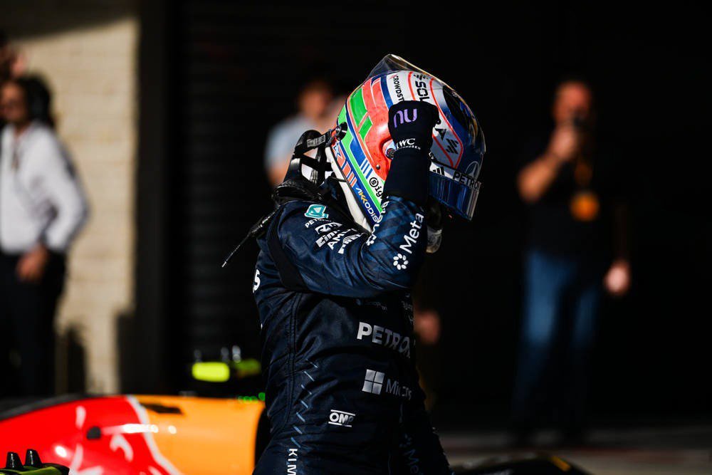 Mercedes F1 driver in navy race suit and helmet raising his arm after a win at the United States Grand Prix, Formula 1