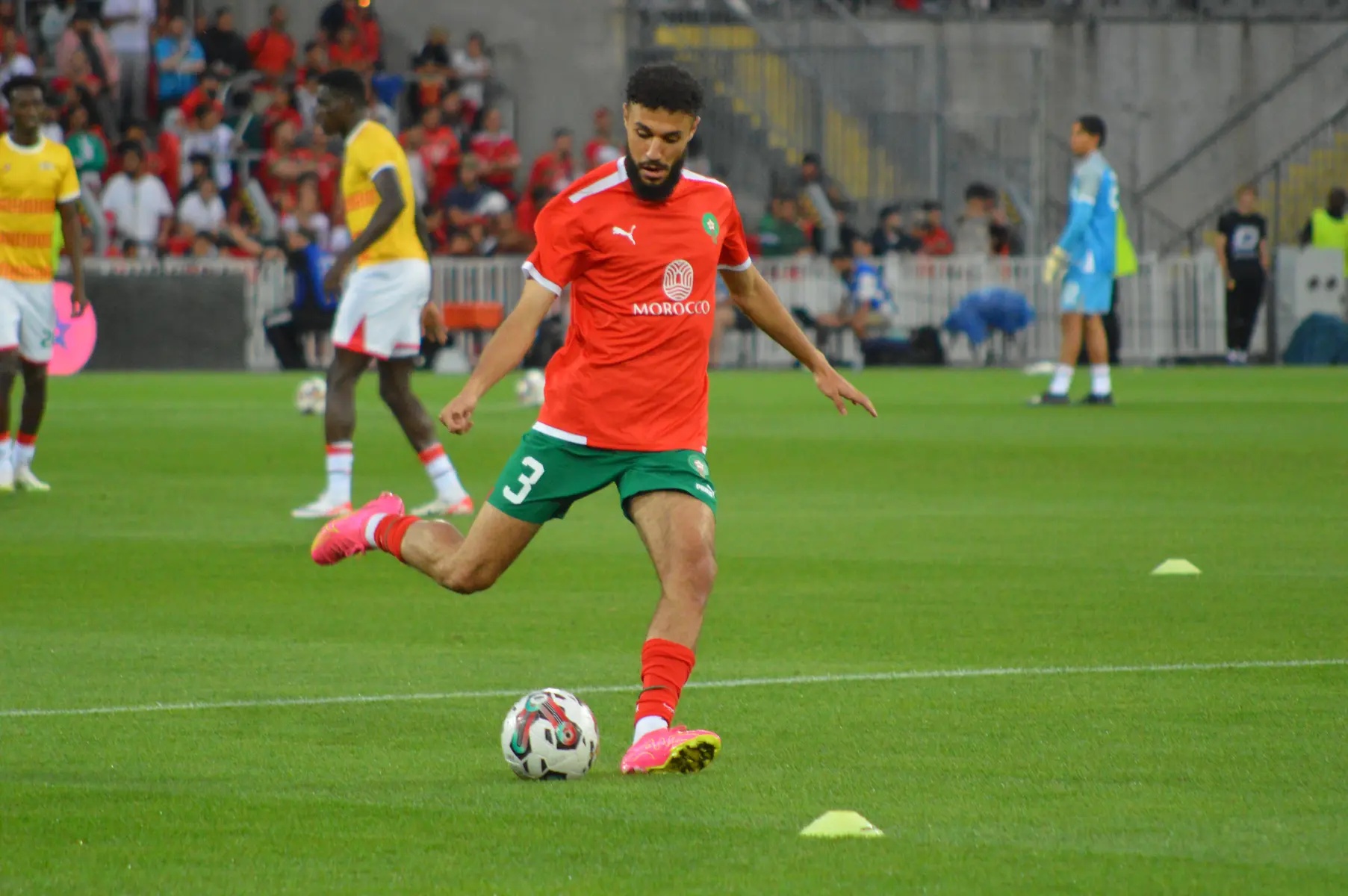 Noussair Mazraoui kicking a football while wearing a Morocco national team kit.