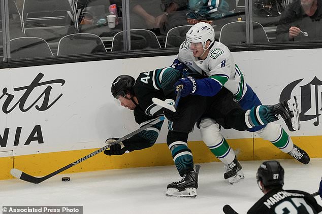 San Jose Sharks left wing Kiefer Sherwood (44) falls toward the puck next to Vancouver Canucks defenseman Zeev Buium during the third period of an NHL hockey game, Thursday, Oct. 29, 2026, in San Jose, Calif. (AP Photo/Jeff Chiu)