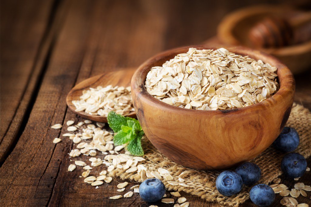 Rolled oats with blueberries, mint, and honey in a wooden bowl.