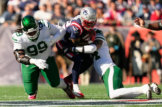 New York Jets defensive lineman T'vondre Sweat (99) and linebacker Jamien Sherwood, right, tackle New England Patriots running back Treveyon Henderson, center, during the first half of an NFL football game in Foxborough, Mass., Sunday, Oct. 18, 2026. (AP Photo/Charles Krupa)