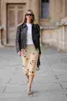 Woman wears jacket, t-shirt, and printed skirt