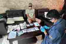 A Russian man is arrested on drug charges as an official examines substances seized from his room in Hua Hin, Prachuap Khiri Khan, on Friday. (Photos: Office of the Narcotics Control Board)