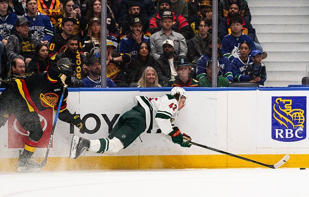 Vancouver Canucks' Max Sasson, left, hits Minnesota Wild's Quinn Hughes (43) during the first period of an NHL hockey game, in Vancouver, British Columbia, Sunday, Oct. 25, 2026. (Jacob Mallari/The Canadian Press via AP)