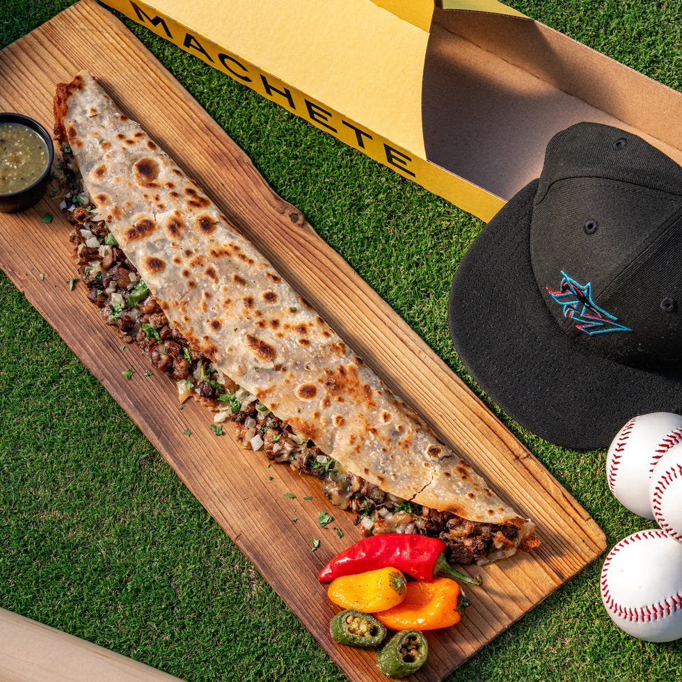 Giant taco served with colorful peppers and baseball accessories.