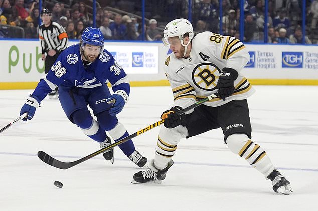 Boston Bruins right wing David Pastrnak (88) works ahead of Tampa Bay Lightning left wing Brandon Hagel (38) during the third period of an NHL hockey game Wednesday, March 27, 2024, in Tampa, Fla. (AP Photo/Chris O'Meara)