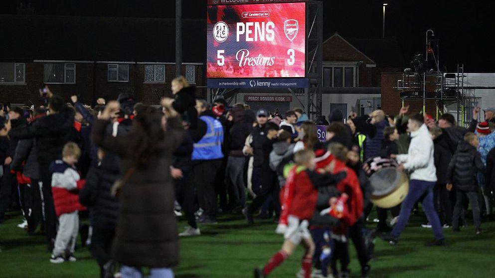 Fans celebrate on the pitch after Fleetwood Town beat Arsenal