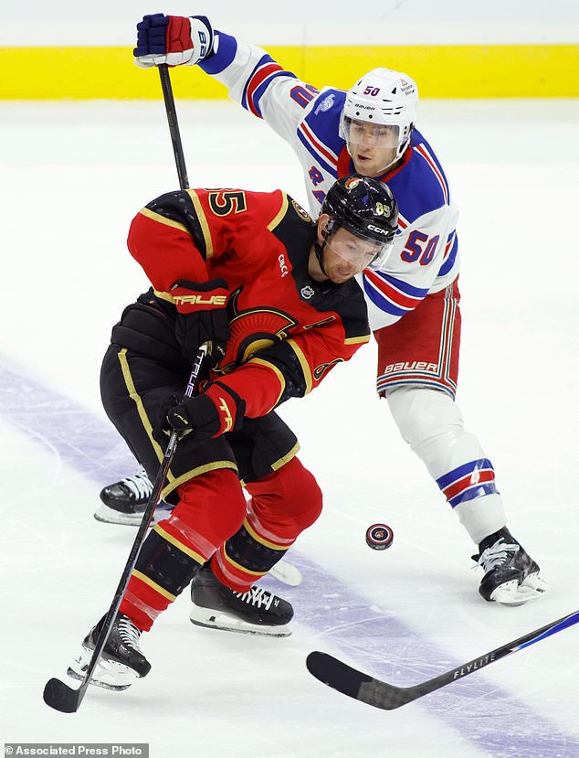 Ottawa Senators' Jake Sanderson (85) and New York Rangers' Will Cuylle (50) try to control the puck during second period NHL hockey action in Ottawa on Saturday, Oct. 24, 2026. (Patrick Doyle/The Canadian Press via AP)