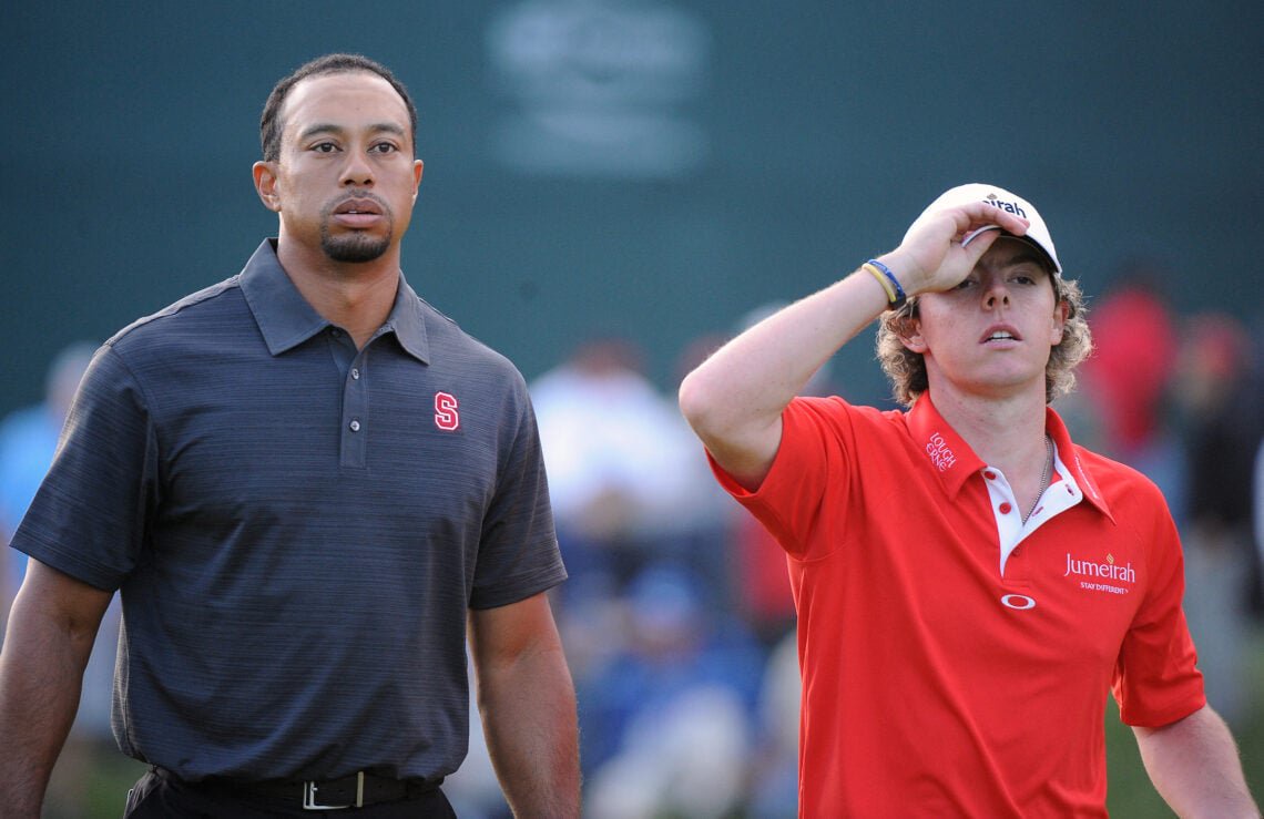 Rory McIlroy (R) of Northern Ireland puts his hat back on as he and Tiger Woods of USA walk off the 18th green after finishing the second round, December 3, 2010 at the 2010 Chevron World Challenge