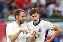 Stones (right) discussing tactics with manager Gareth Southgate during the win over Slovakia
