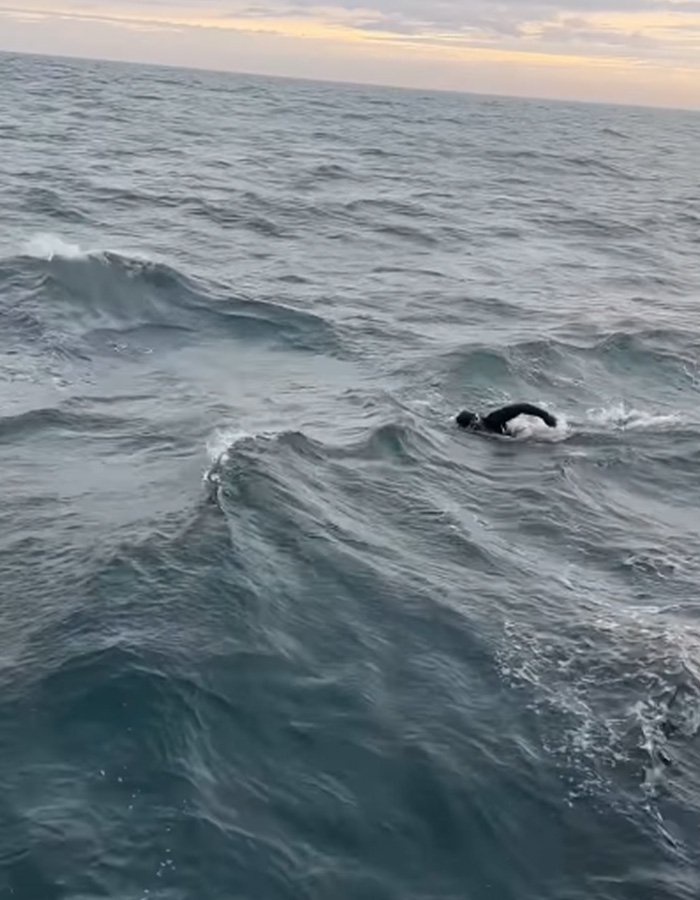Extreme swimmer navigating through rough ocean waves during a long-distance challenge.
