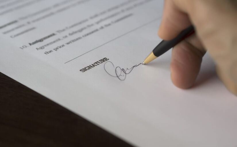 Hand signing a contract with a pen