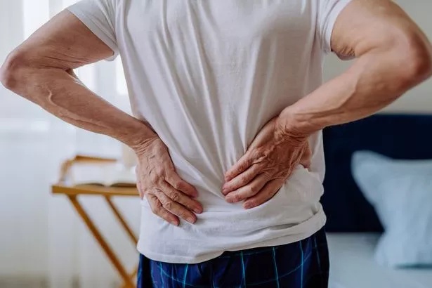 A photo of a man holding his lower back