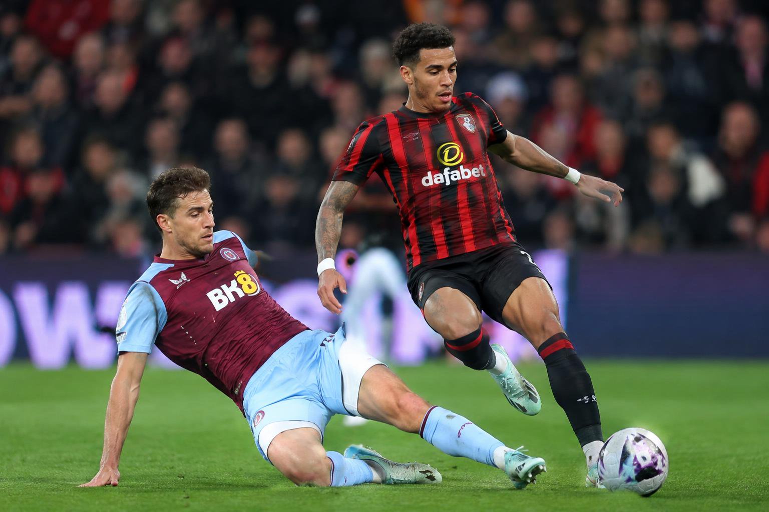 Aston Villa's Pau Torres is sliding a tackle against Bournemouth's Justin Kluivert in the Premier League