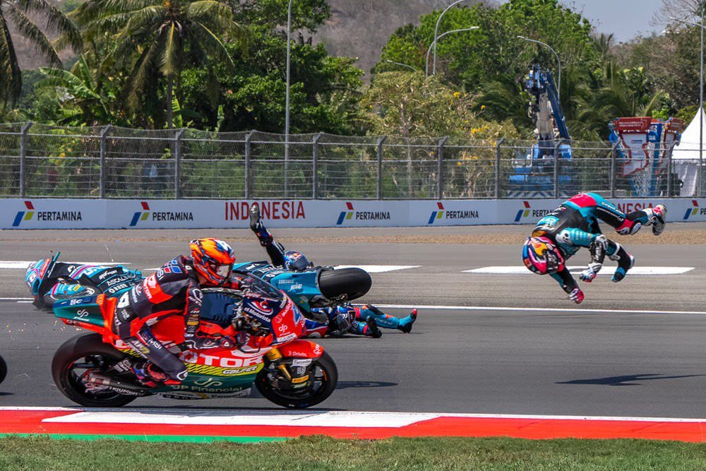 Riders crash on track at Indonesia's Mandalika circuit, one tumbling through the air, with Pertamina branding on the barriers