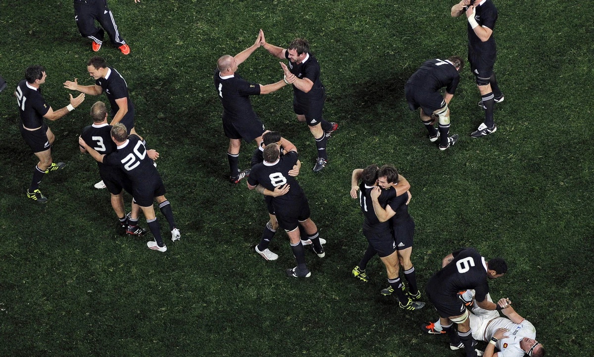 New Zealand All Blacks Jerome Kaino helps up France's Imanol Harinordoquy as his teammates celebrate after their Rugby World Cup final win over France at Eden Park in Auckland, New Zealand, Sunda ...
