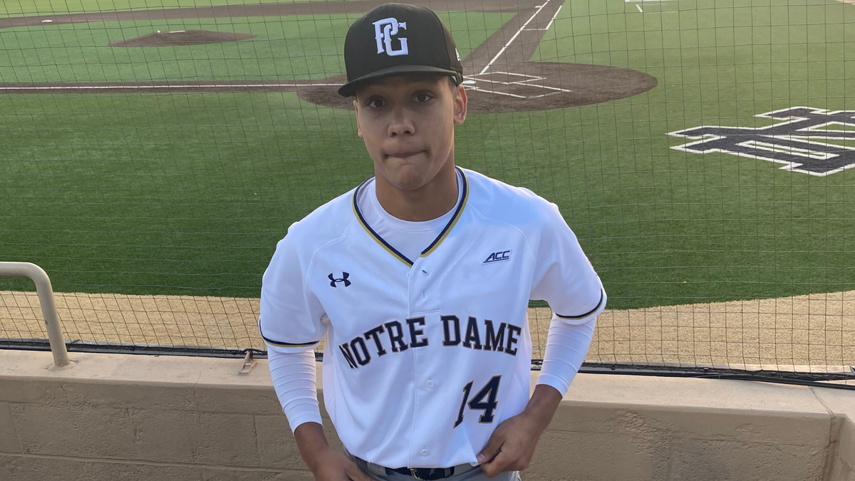 tan teen boy in a notre dame baseball uniform and cap before playing a game