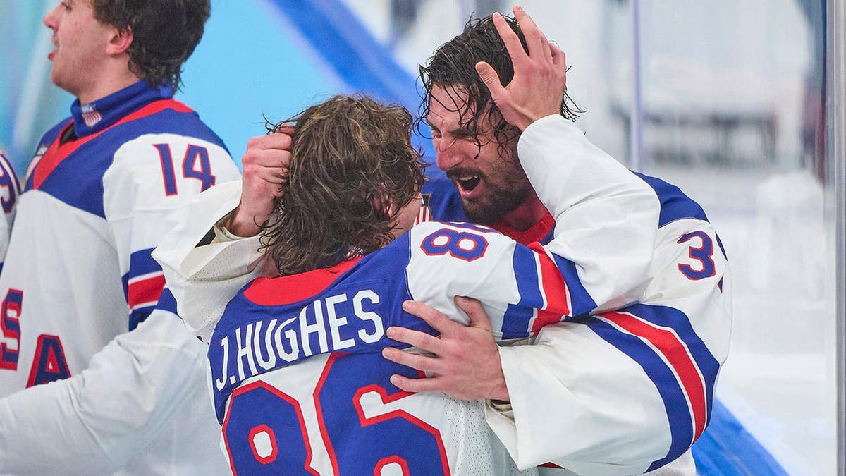 Jack Hughes celebrates with Connor Hellebuyck after Team United States wins gold medal in men's ice hockey.