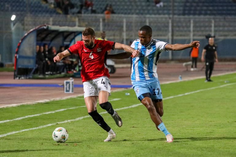 Egyptian player Omar Abdel Wahed challenges Botswana player Chicco Molefe on the field.