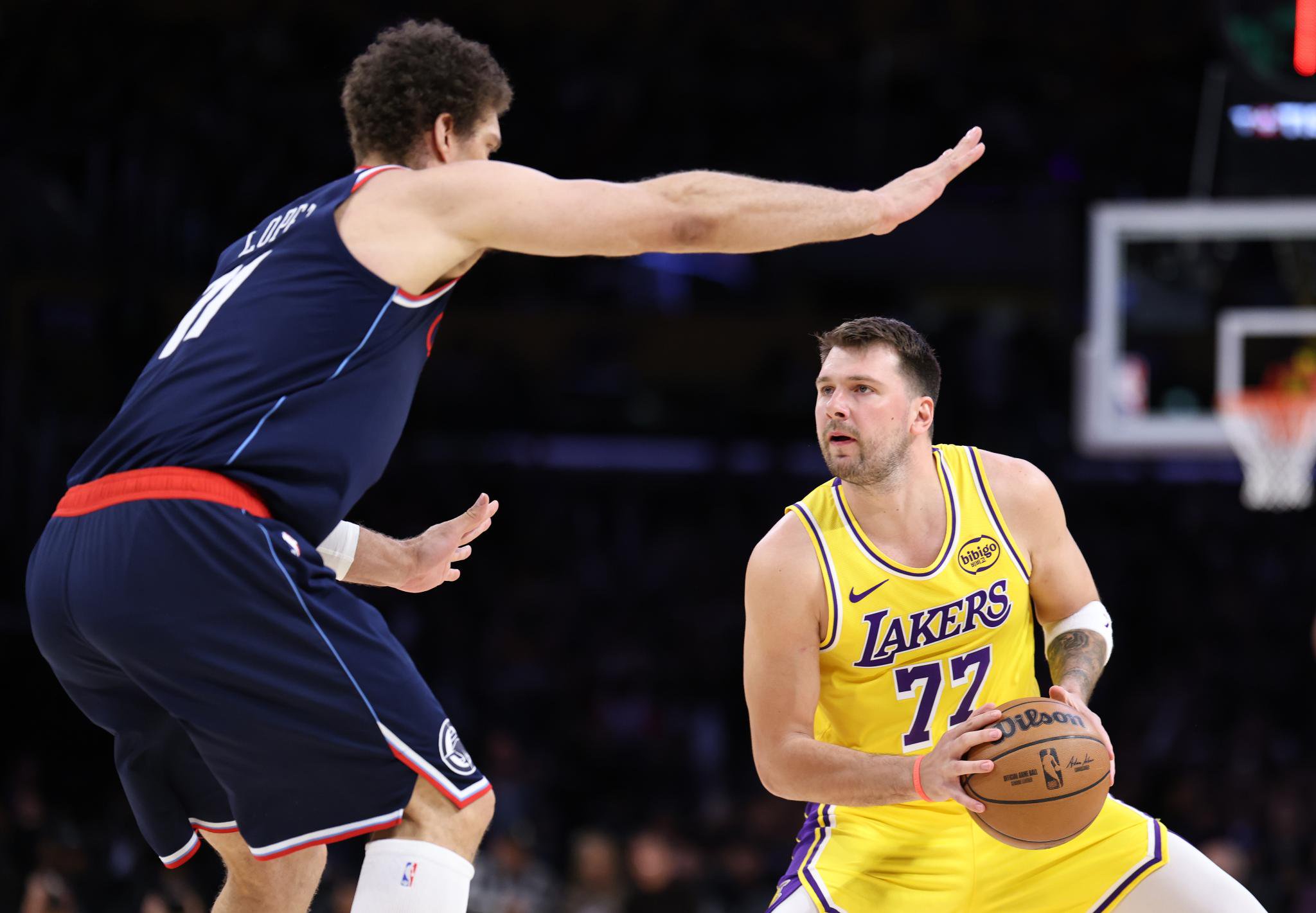 Luka Doncic protecting the ball from Brook Lopez.