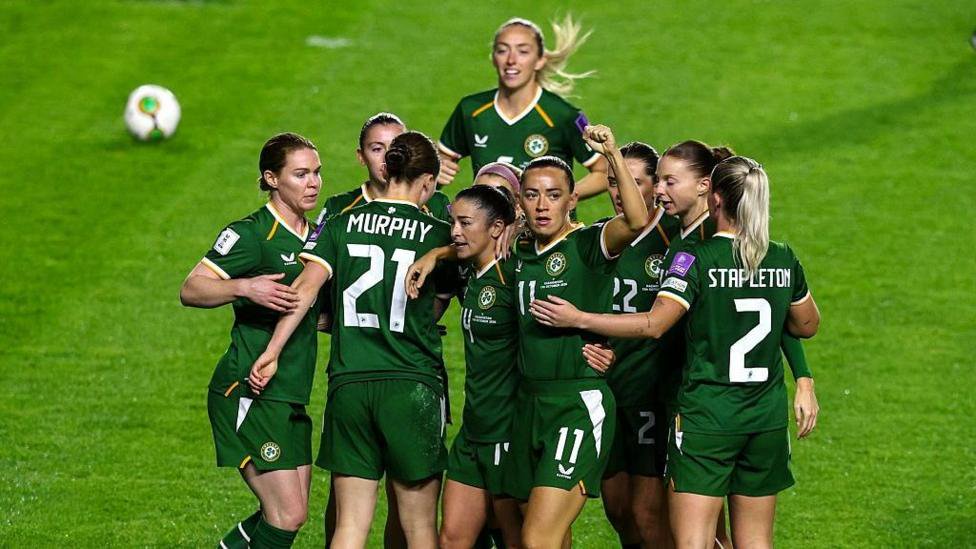 Republic of Ireland players, in all-green kit, celebrate together on the pitch