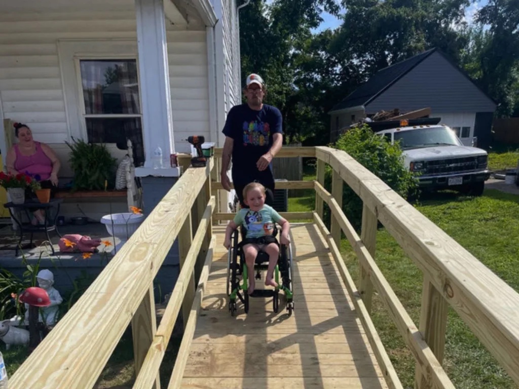 Maverick smiles in his wheelchair on his brand-new wooden wheelchair ramp