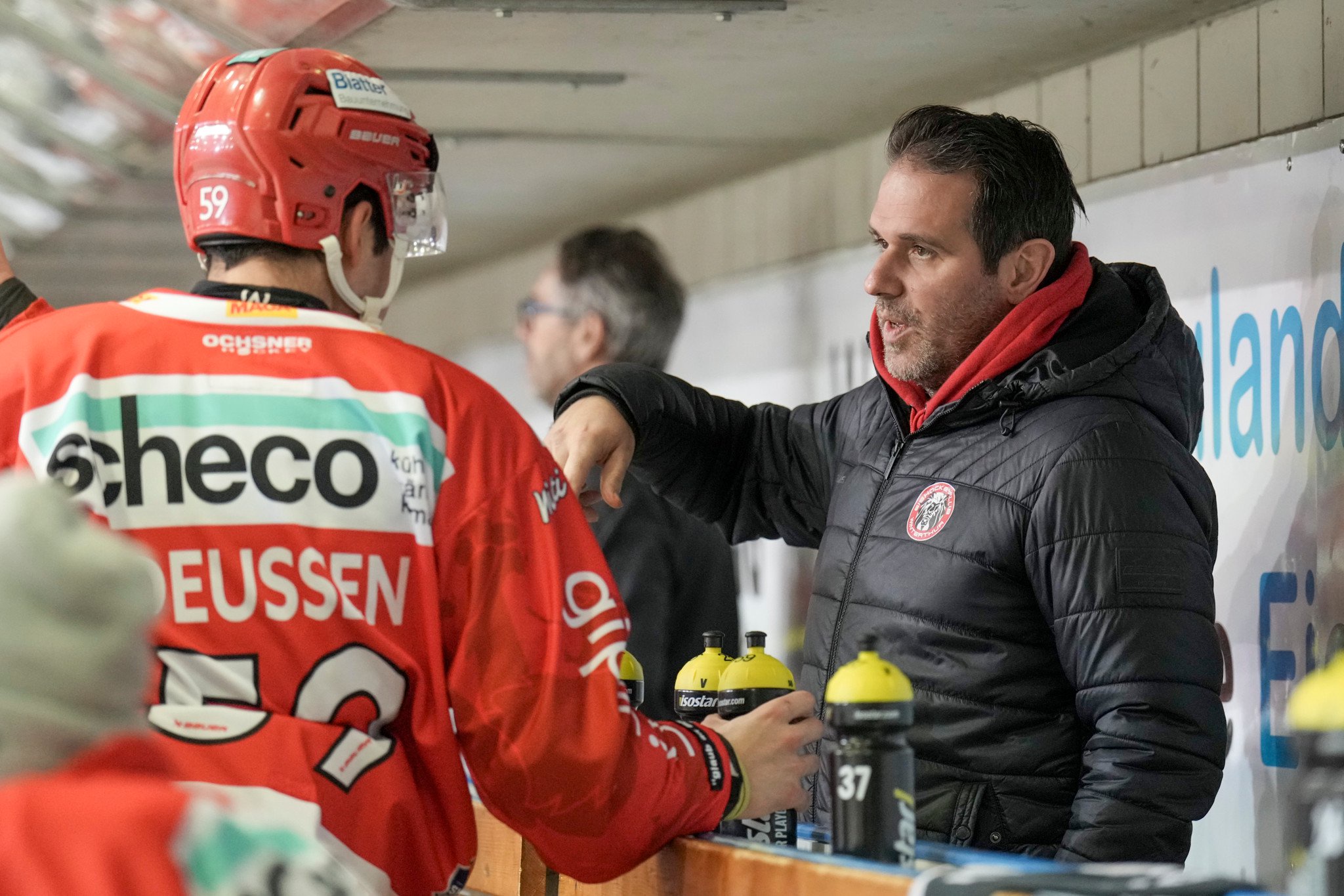 Eishockeyspieler Luca Deussen (EHC Winterthur, #59) im Gespräch mit Assistenztrainer Adrian Wichser auf der Spielerbank, Swiss League.