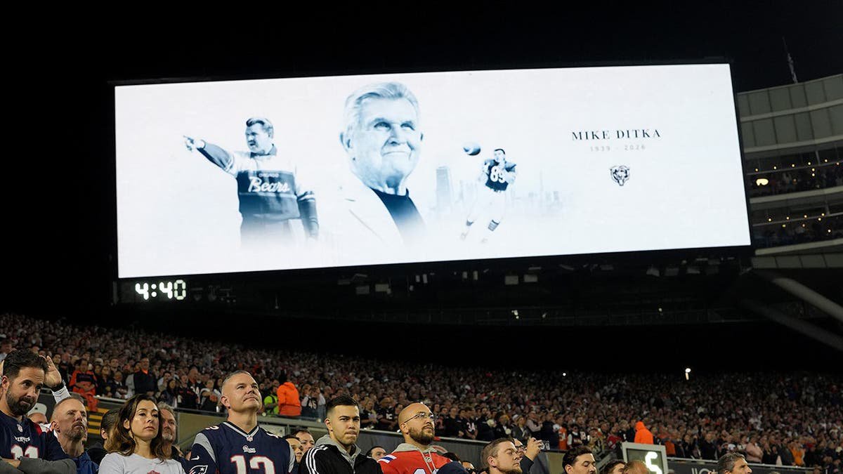 Fans stand during a moment of silence for Mike Ditka at Soldier Field.